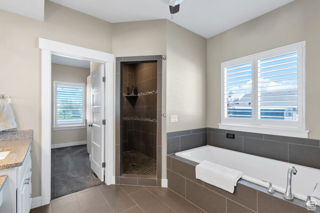 Full bathroom featuring a bath, vanity, a shower stall, tile patterned flooring, and baseboards