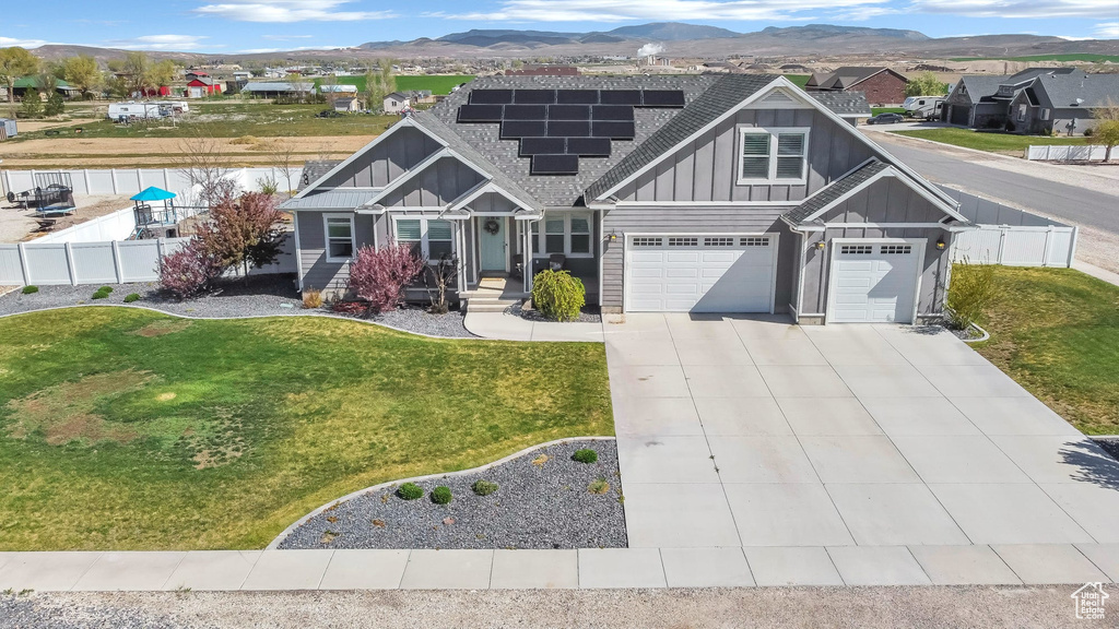 Craftsman inspired home featuring board and batten siding, roof mounted solar panels, a mountain view, concrete driveway, and an attached garage