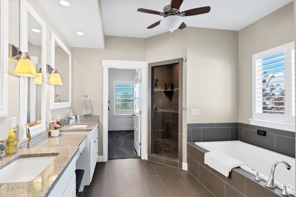 Bathroom featuring double vanity, ceiling fan, a stall shower, a bath, and tile patterned floors