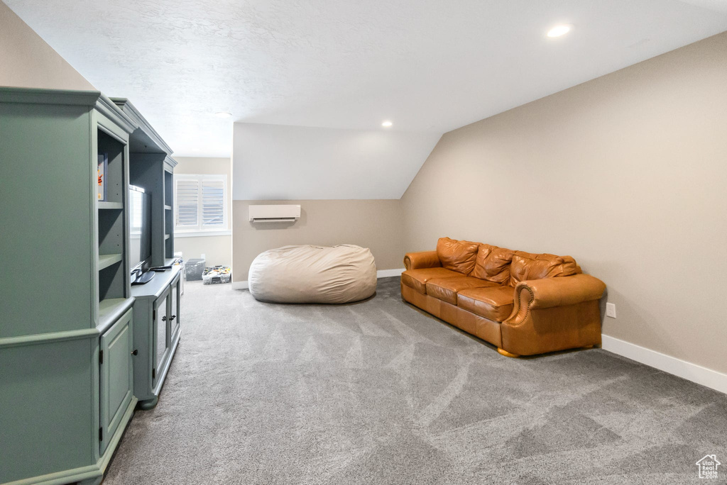 Living area with carpet, baseboards, a wall unit AC, lofted ceiling, and recessed lighting