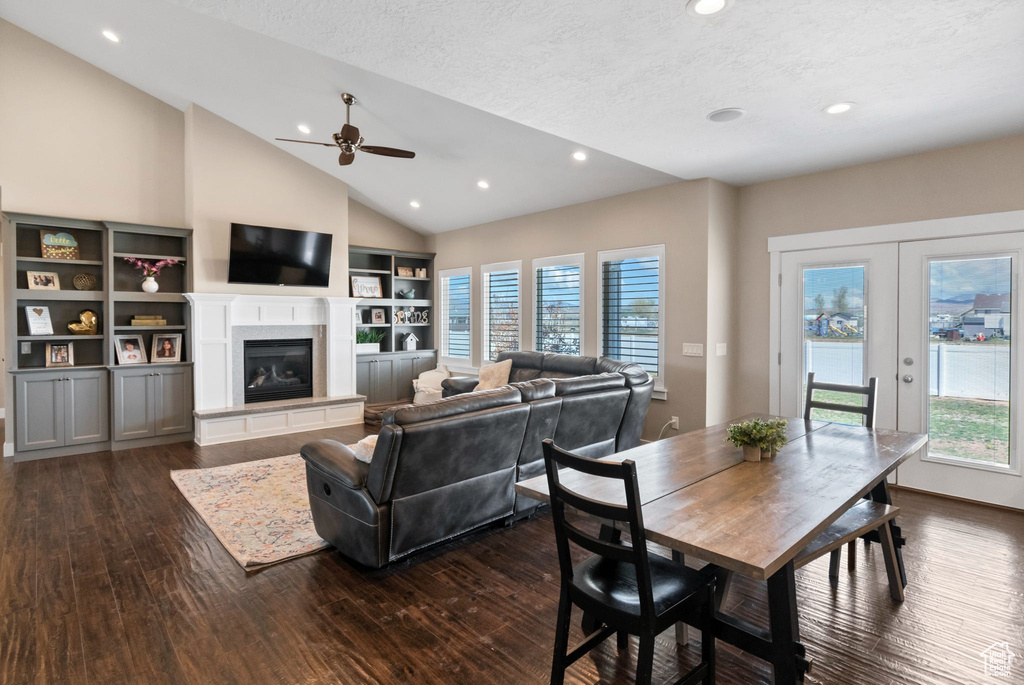 Dining space with dark wood-type flooring, plenty of natural light, ceiling fan, vaulted ceiling, and a textured ceiling