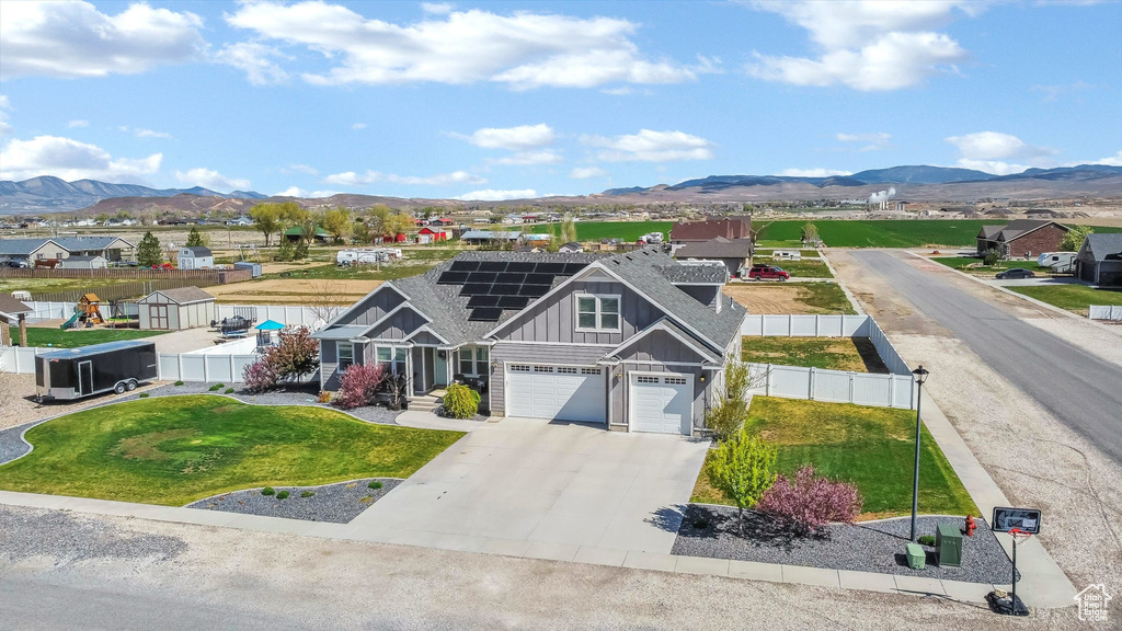 View of front of home featuring board and batten siding, solar panels, a mountain view, concrete driveway, and a residential view
