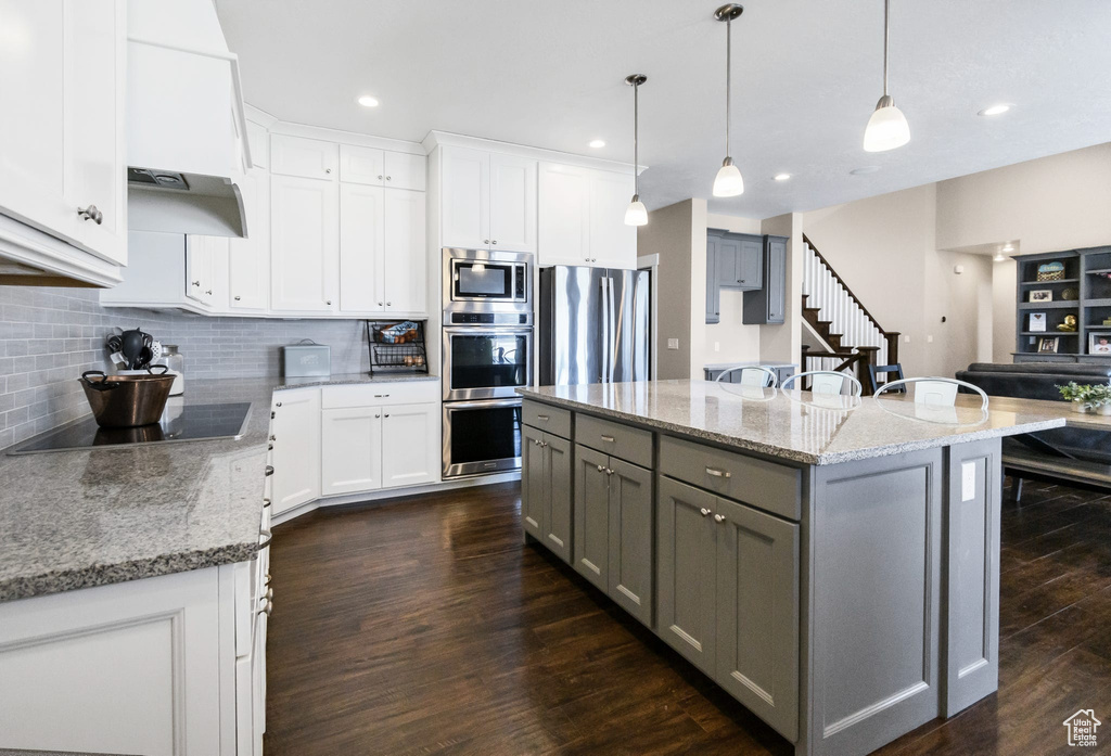 Kitchen with gray cabinets, stainless steel appliances, light stone counters, tasteful backsplash, and recessed lighting