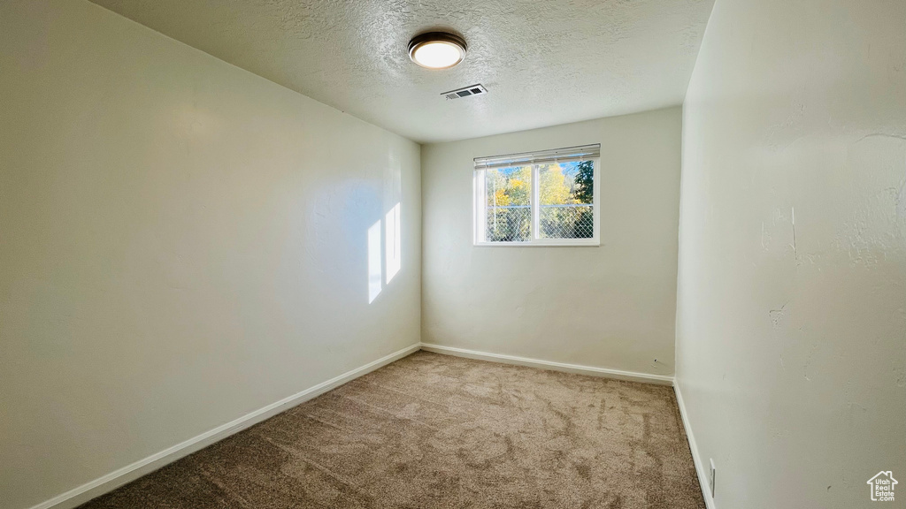 Unfurnished room featuring carpet, baseboards, and a textured ceiling