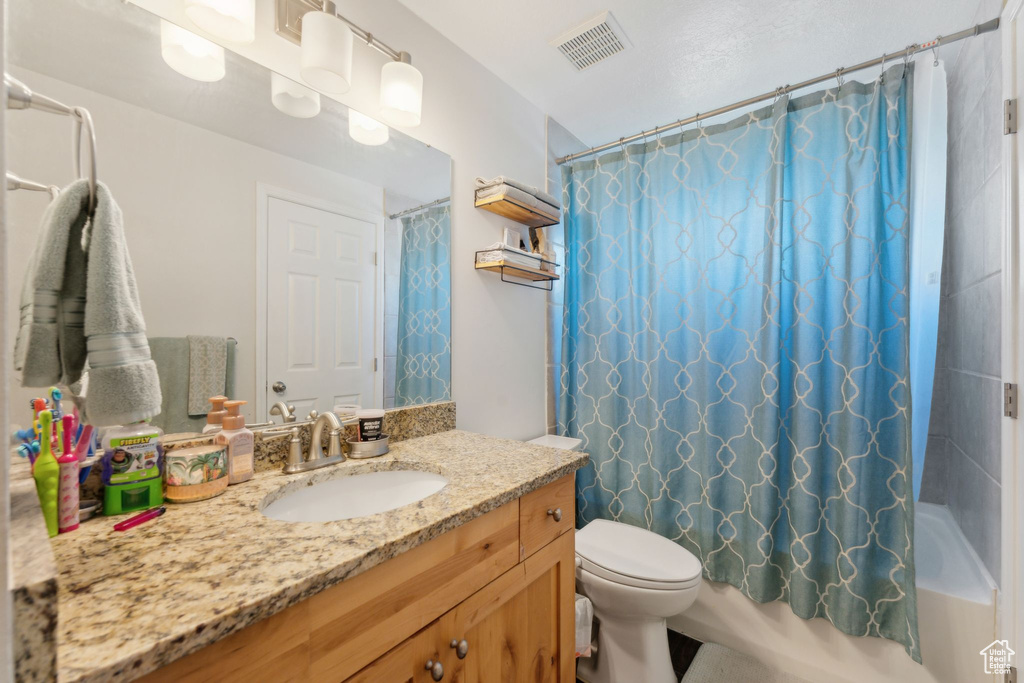 Bathroom featuring vanity, toilet, and shower / bath combo with shower curtain