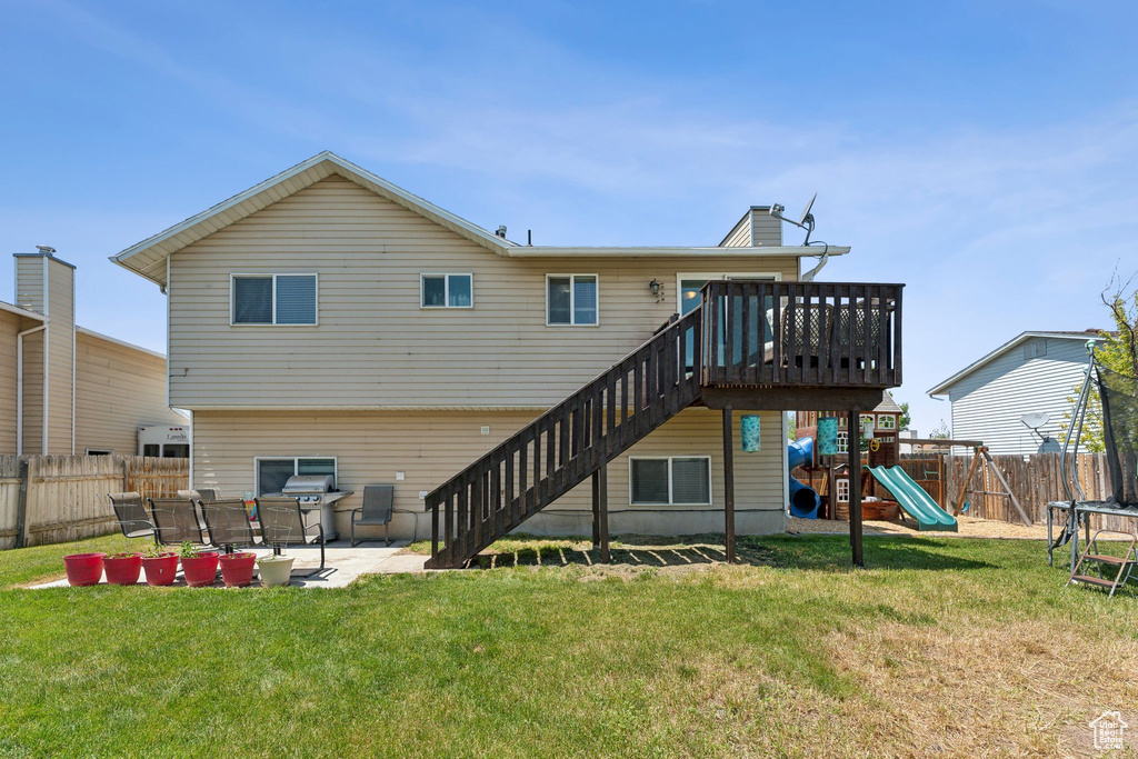 Rear view of house featuring a trampoline, a patio, stairs, and a playground