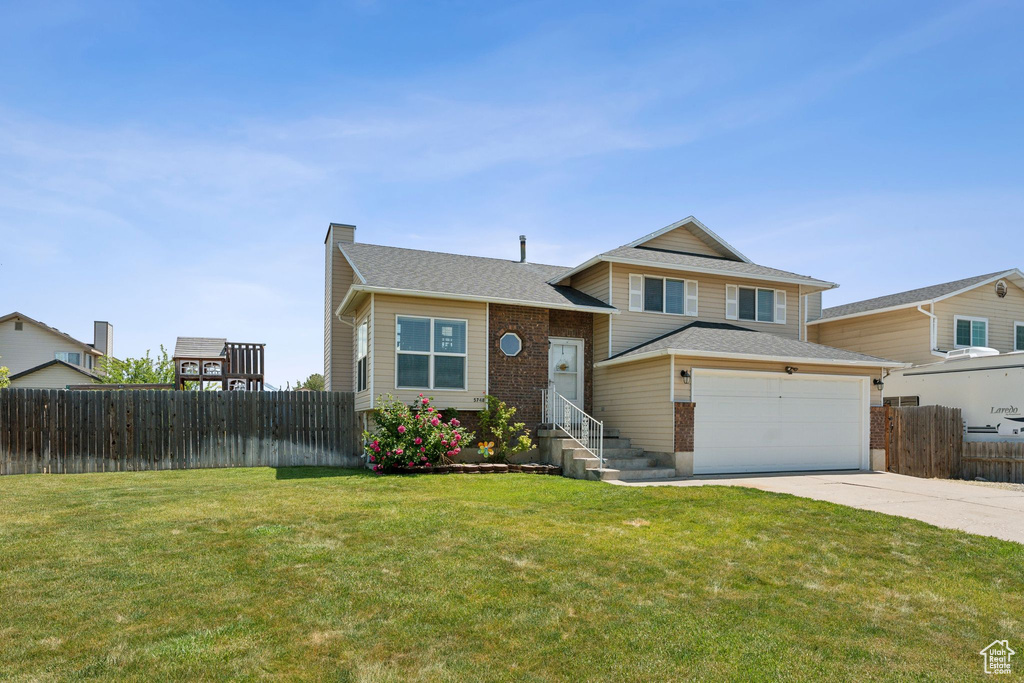 Tri-level home with concrete driveway, a chimney, and roof with shingles