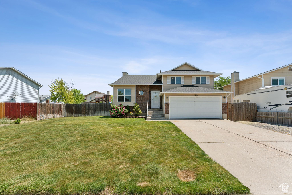 Tri-level home featuring driveway, brick siding, and a garage
