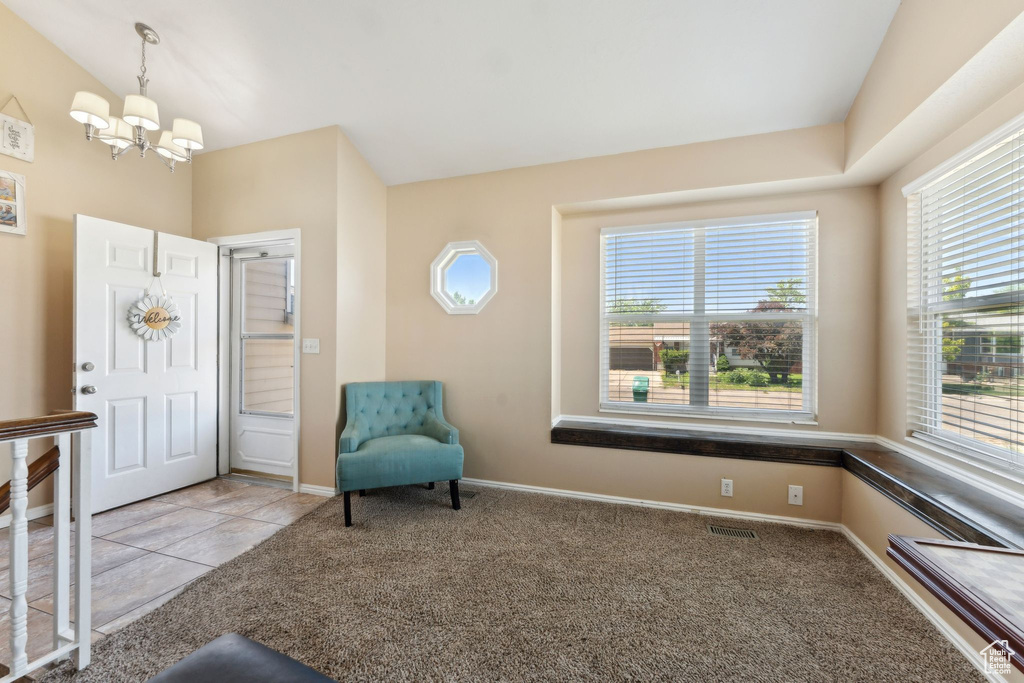 Foyer entrance with a chandelier, carpet, and baseboards