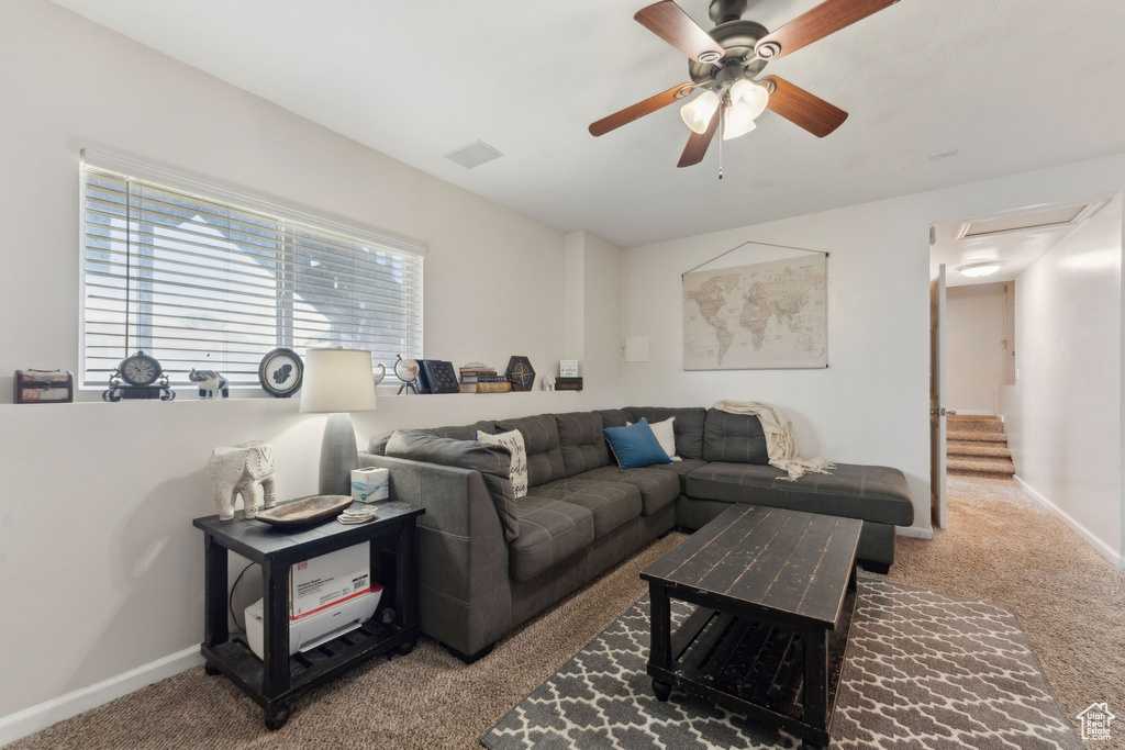 Carpeted living area with ceiling fan and baseboards