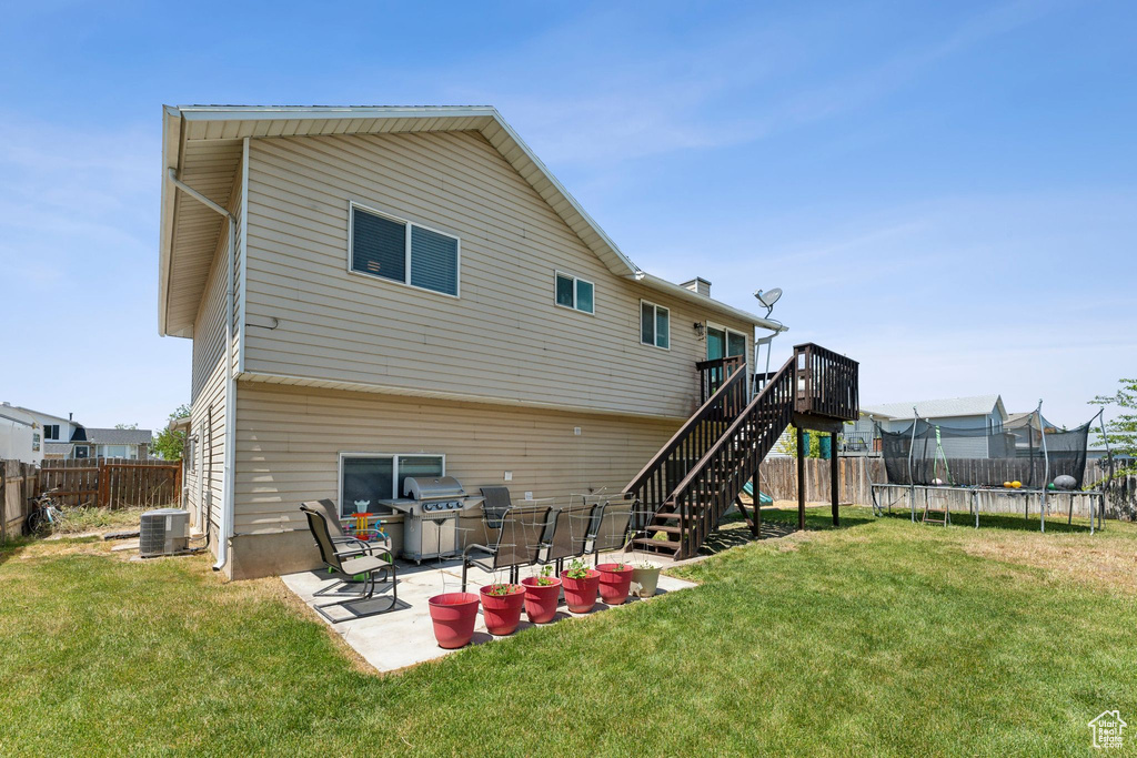 Rear view of house with a trampoline, stairway, central AC, a deck, and a patio