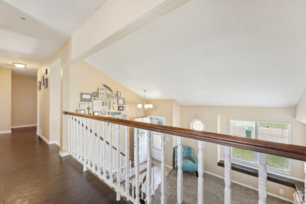 Corridor with an upstairs landing, baseboards, a chandelier, wood finished floors, and lofted ceiling