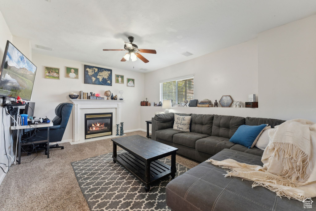 Living area with carpet, a ceiling fan, a glass covered fireplace, an office area, and baseboards