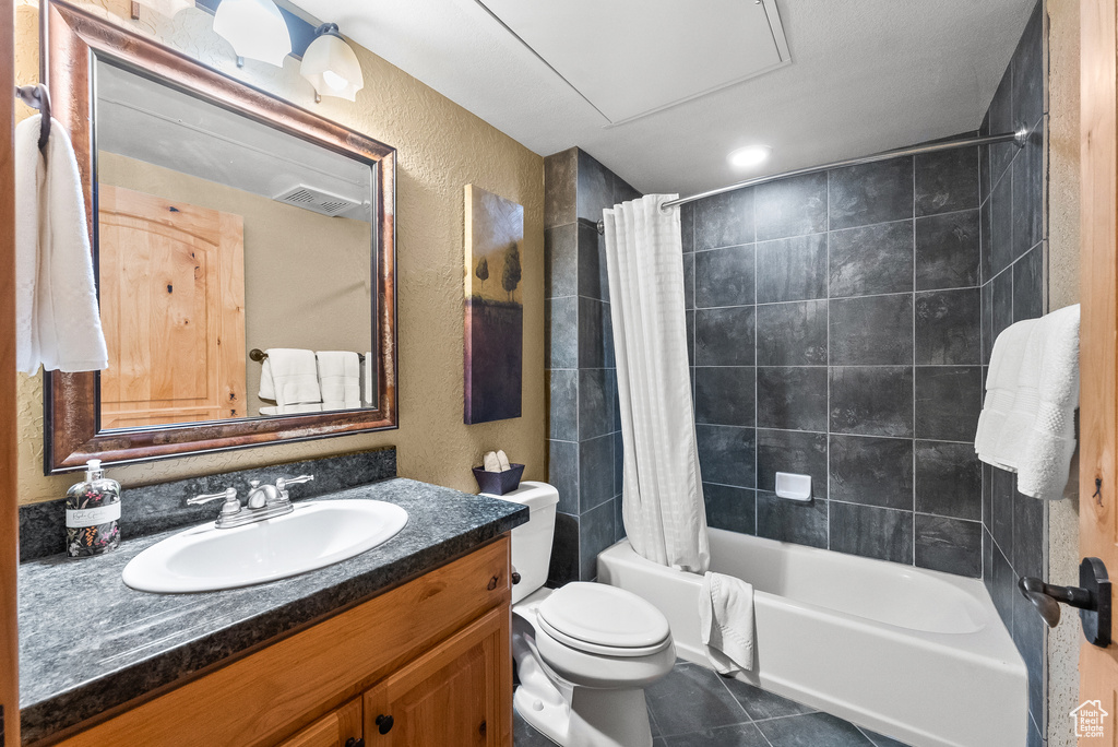 Full bathroom featuring vanity, a textured wall, shower / tub combo, toilet, and tile patterned floors