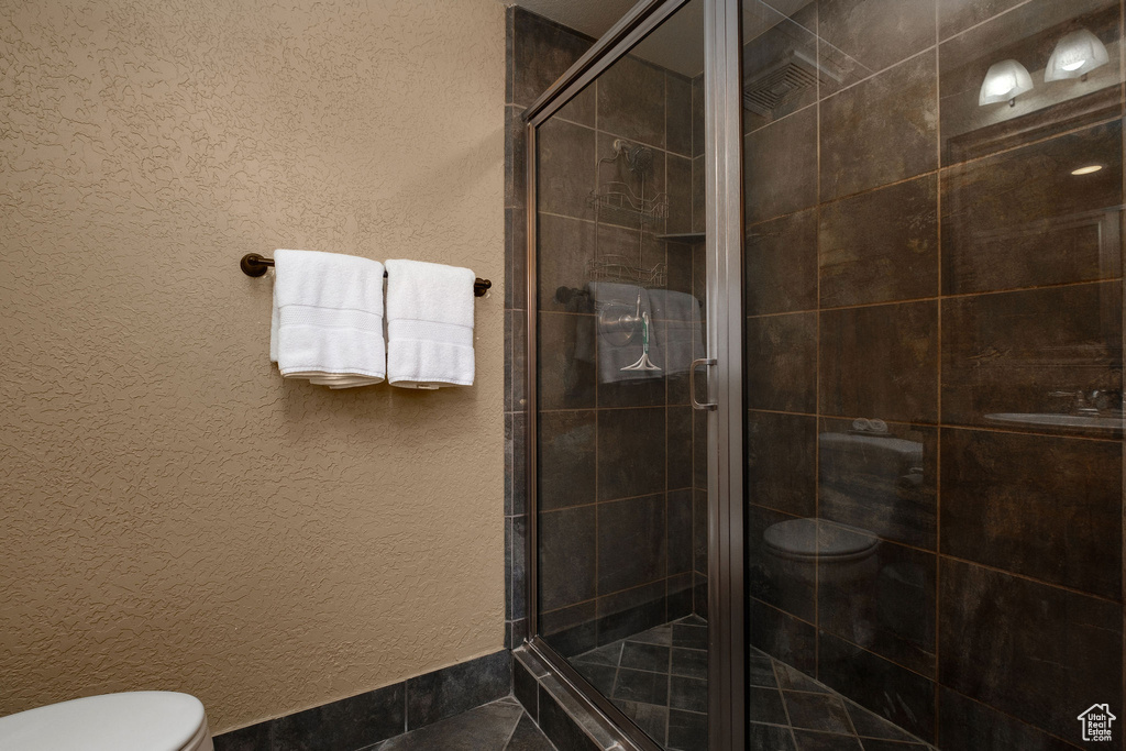 Bathroom featuring toilet and a stall shower