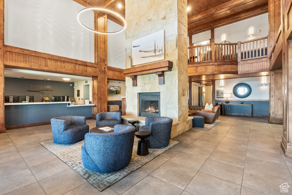 Tiled living area with a high ceiling, a fireplace, and wood ceiling