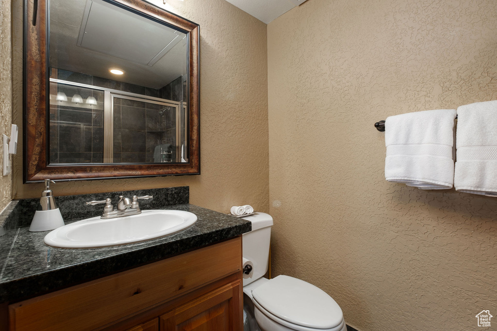 Full bath with a textured wall, toilet, vanity, and tiled shower
