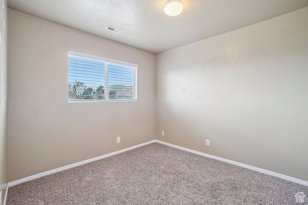 Carpeted spare room featuring baseboards