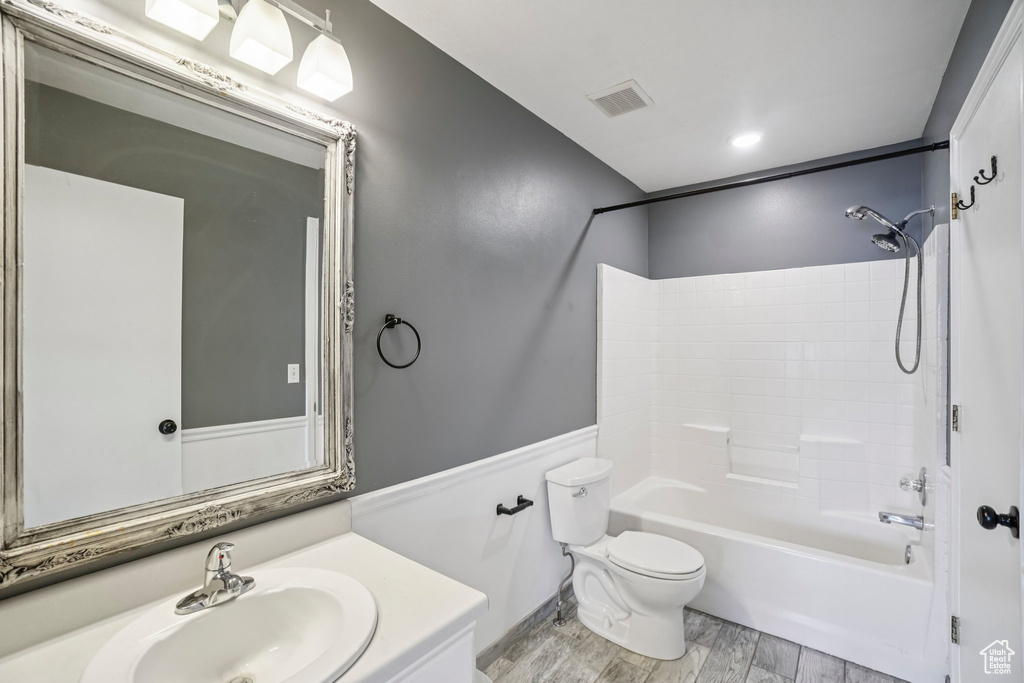 Full bath featuring toilet, vanity, wood finished floors, and bathing tub / shower combination