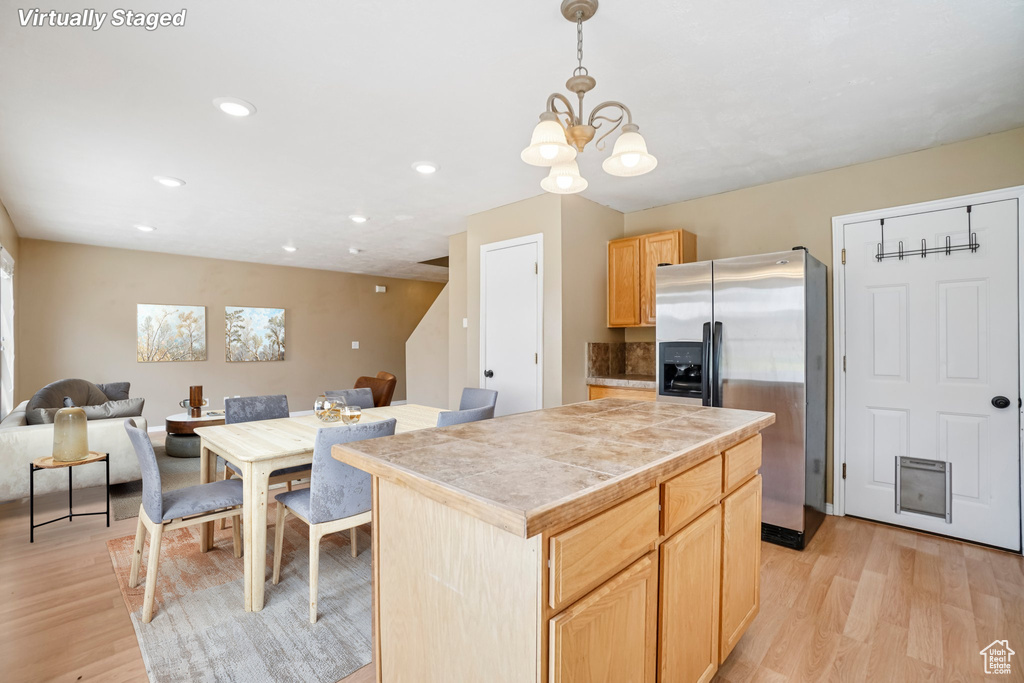 Kitchen with stainless steel fridge, light wood finished floors, a chandelier, open floor plan, and light brown cabinets