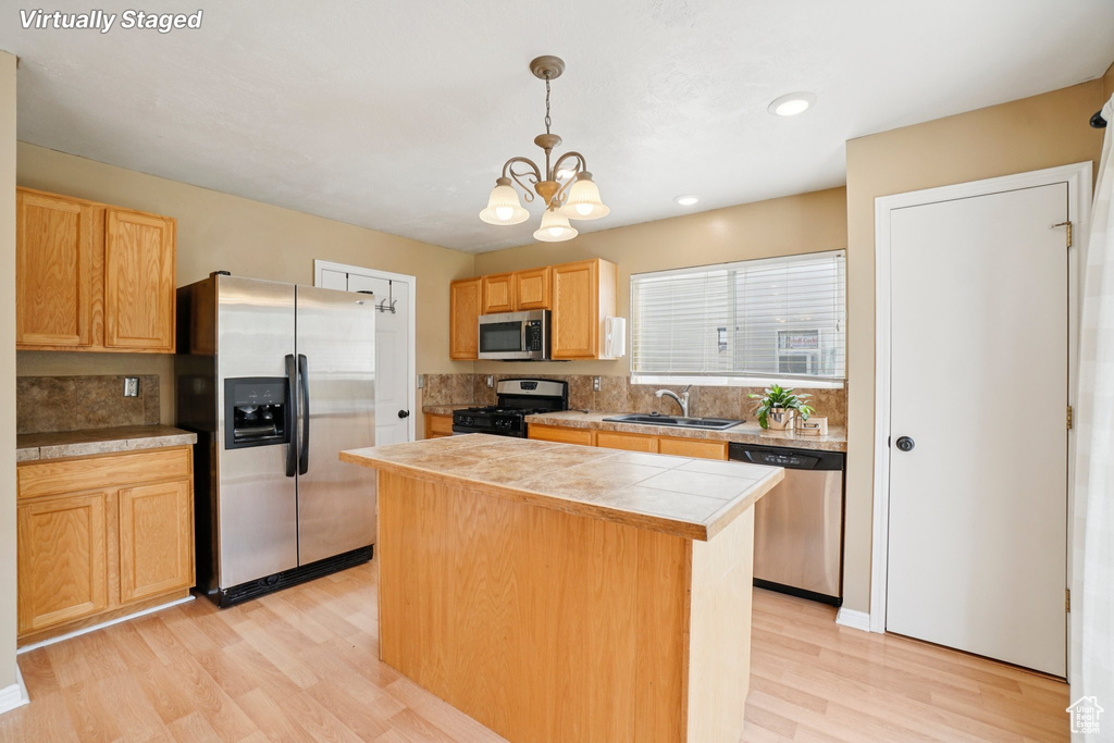 Kitchen featuring stainless steel appliances, a sink, light wood-style flooring, a center island, and recessed lighting