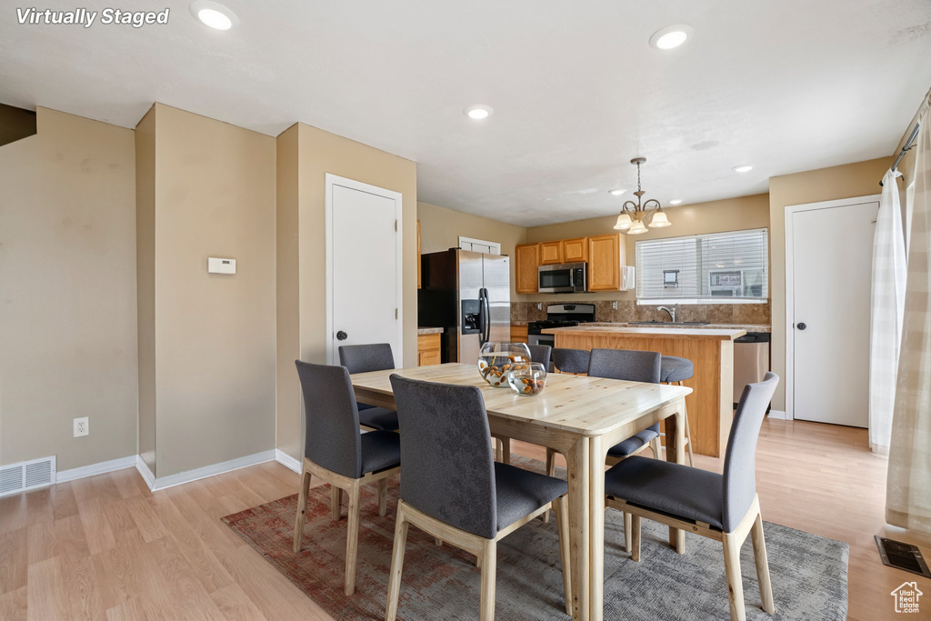 Dining space with a chandelier, light wood finished floors, recessed lighting, and baseboards