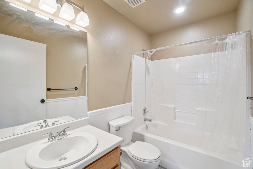 Full bathroom with shower / bath combo, toilet, vanity, and recessed lighting