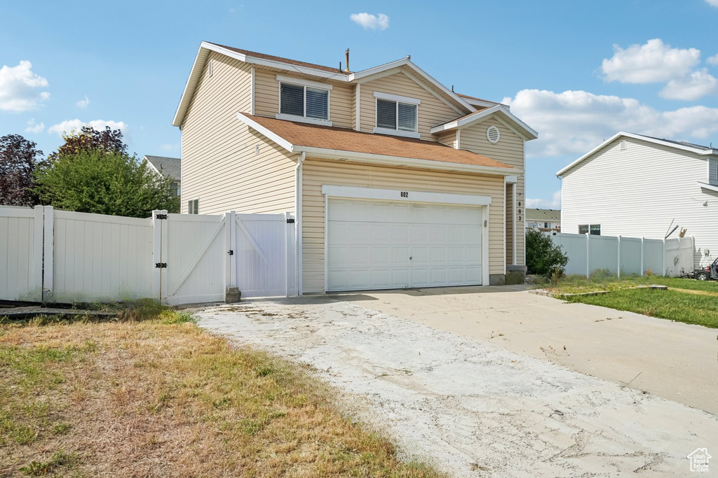 Traditional-style house featuring a gate, driveway, and a garage