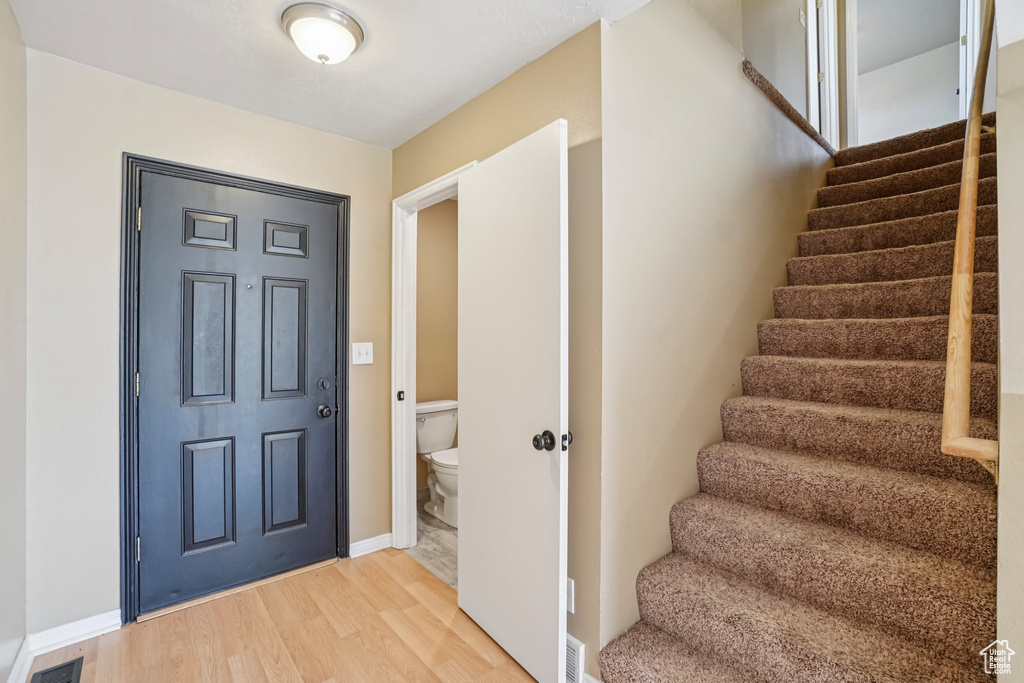 Foyer with stairway, light wood finished floors, and baseboards