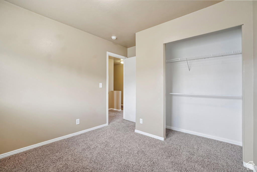 Unfurnished bedroom featuring carpet, baseboards, and a closet
