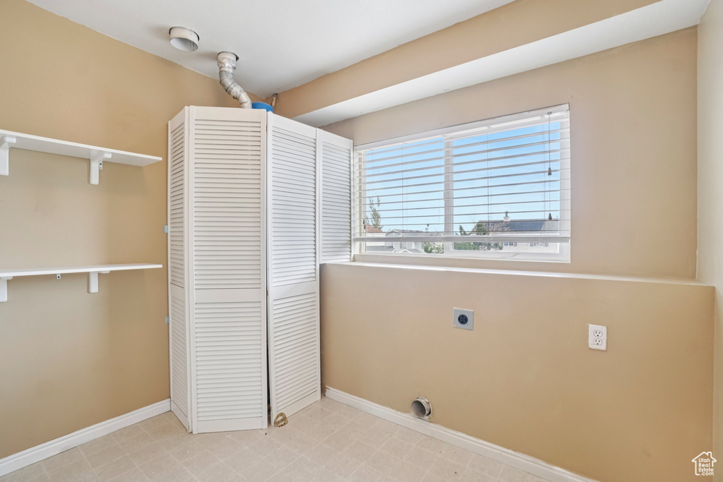 Washroom featuring electric dryer hookup, baseboards, and light flooring