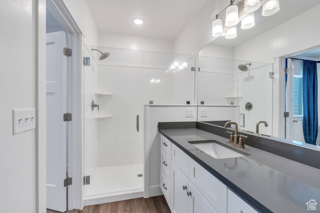 Full bathroom featuring a shower stall, vanity, and wood finished floors