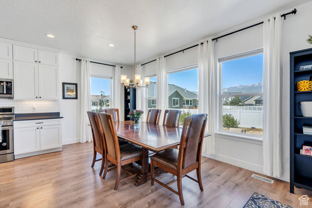 Dining room with a chandelier, light wood-style floors, recessed lighting, and baseboards