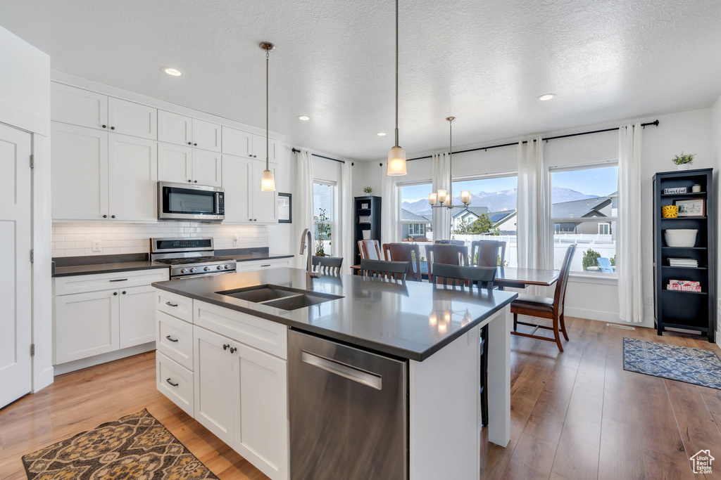 Kitchen featuring appliances with stainless steel finishes, a sink, dark countertops, healthy amount of natural light, and recessed lighting