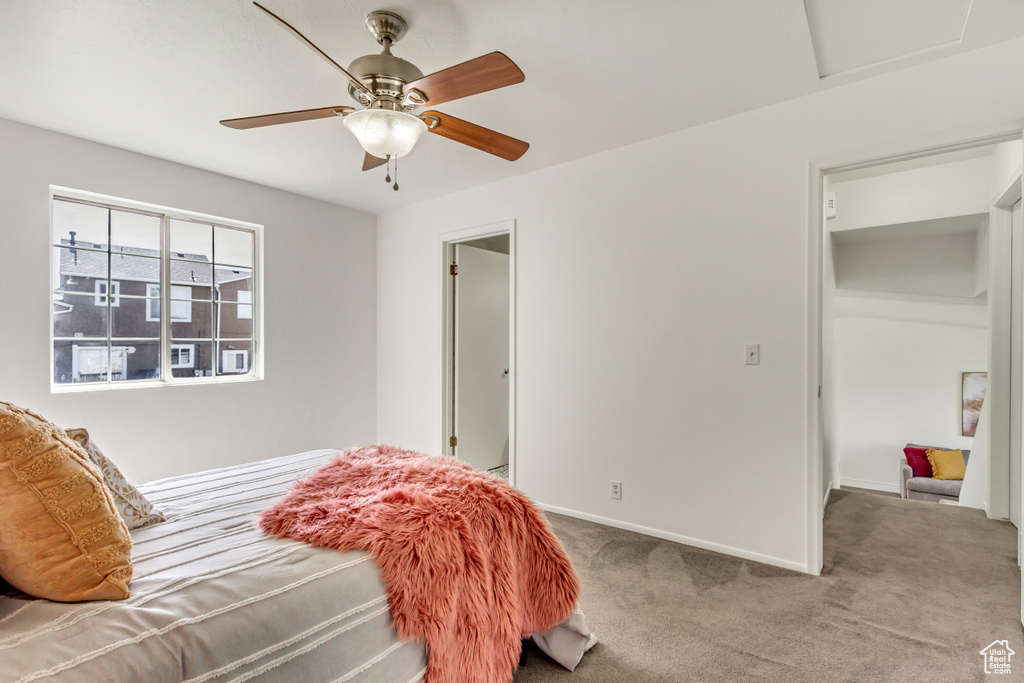 Carpeted bedroom featuring baseboards, a ceiling fan, and attic access
