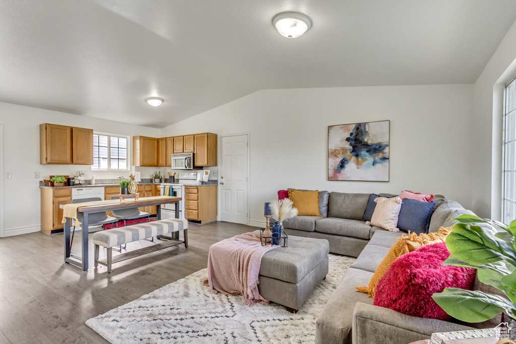 Living area featuring vaulted ceiling, light wood-style floors, and baseboards