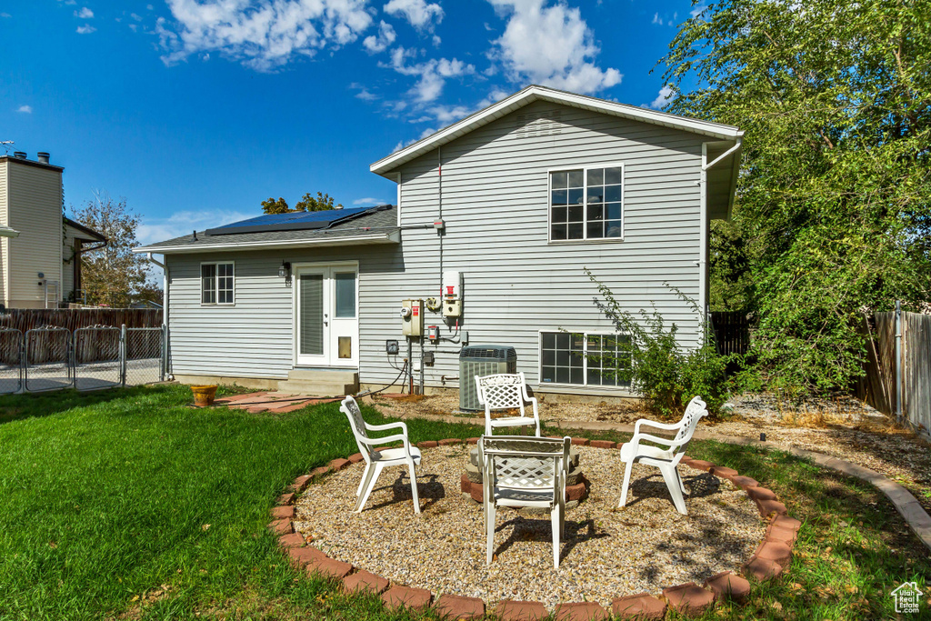 Back of house with roof mounted solar panels, entry steps, a fire pit, central air condition unit, and french doors