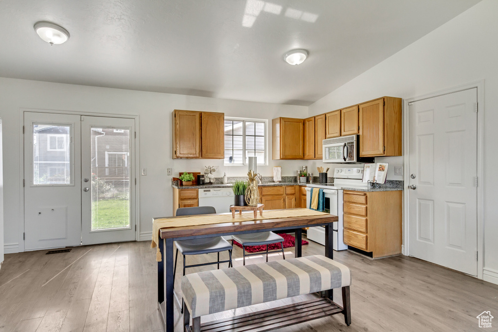 Kitchen featuring white appliances, lofted ceiling, and light wood-type flooring