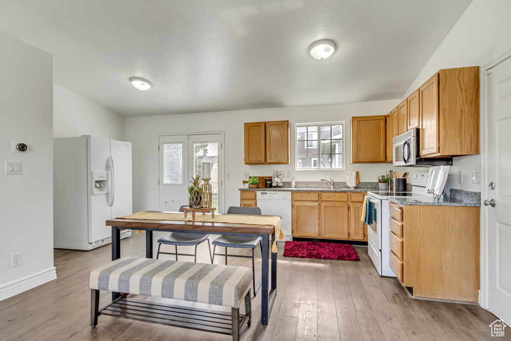 Kitchen with white appliances, light wood-type flooring, a sink, and baseboards