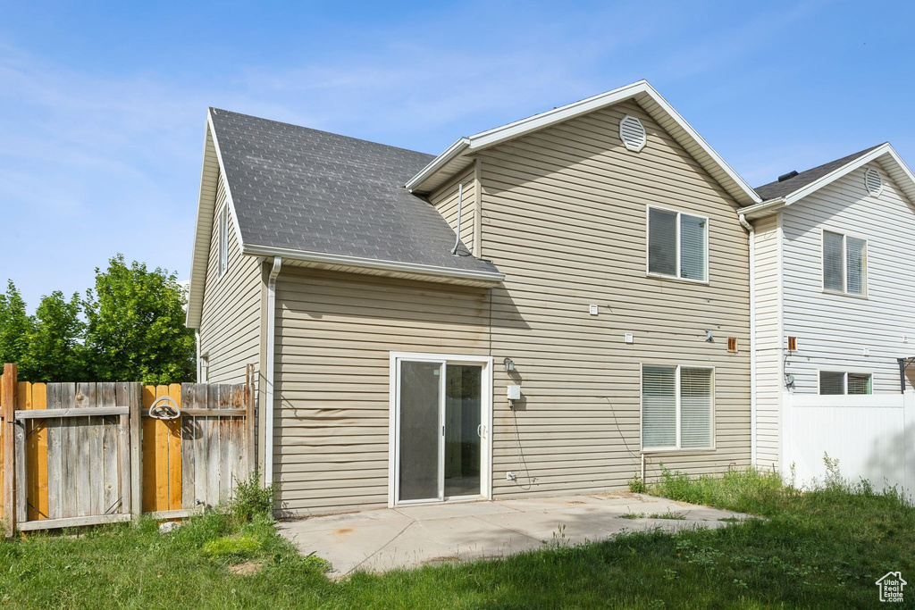 Rear view of house with roof with shingles, a gate, and a patio