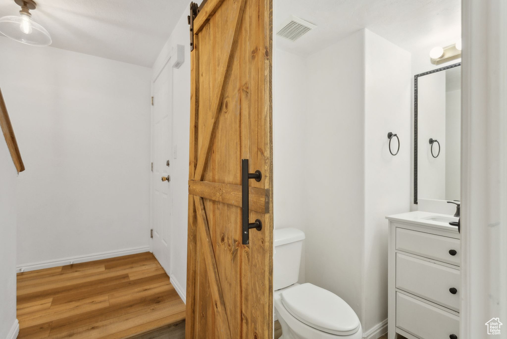Bathroom with vanity, toilet, wood finished floors, and baseboards