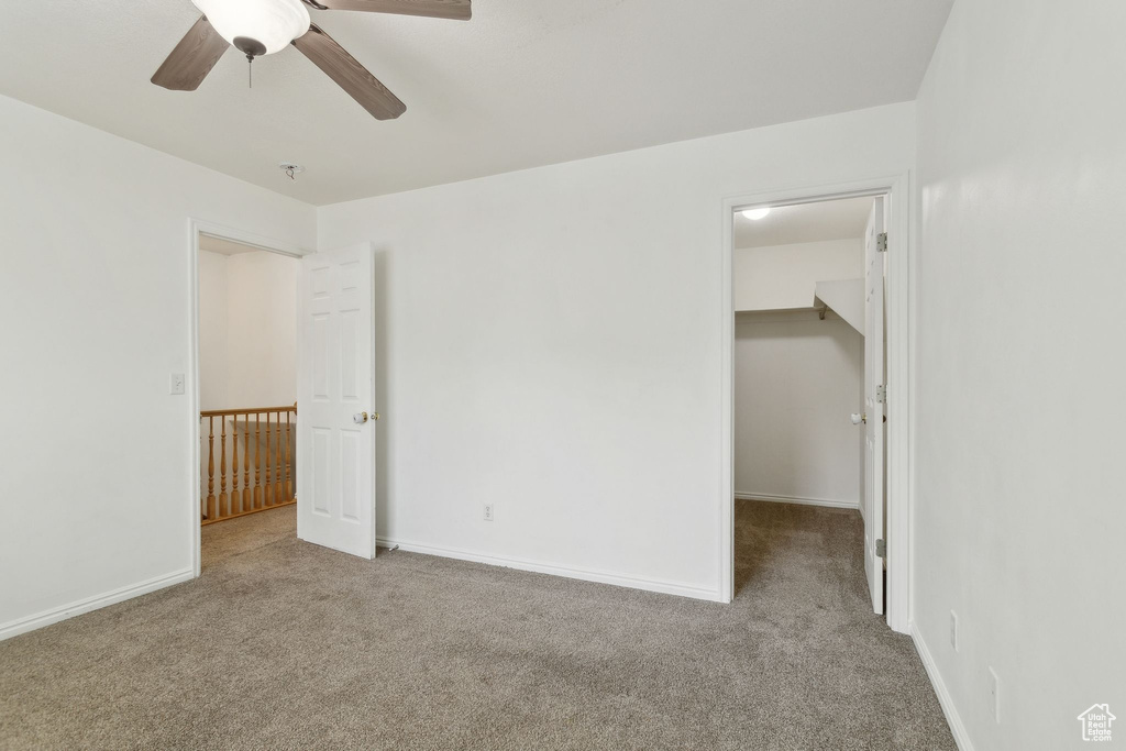 Empty room with carpet floors, ceiling fan, baseboards, and a pendent fire sprinkler