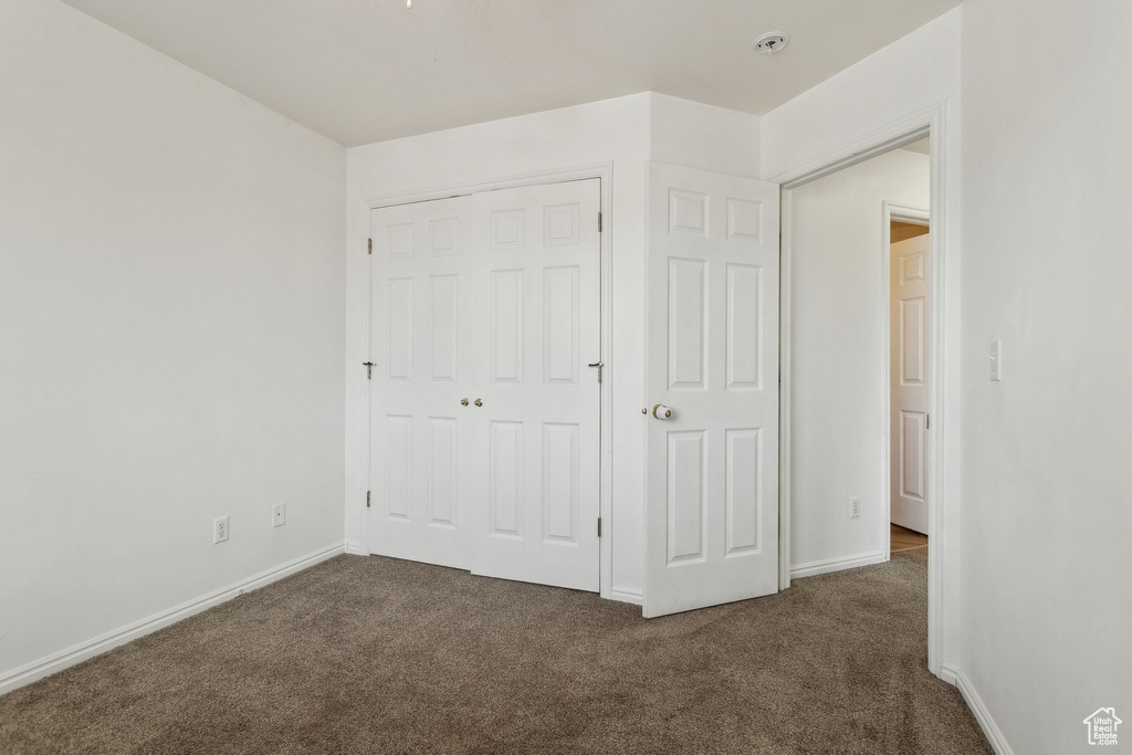 Unfurnished bedroom featuring carpet floors, a closet, and baseboards