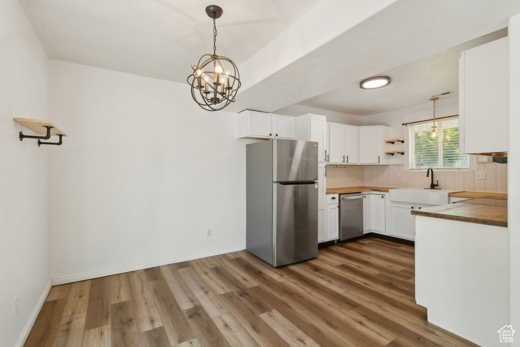 Kitchen featuring appliances with stainless steel finishes, a sink, dark wood finished floors, tasteful backsplash, and white cabinetry