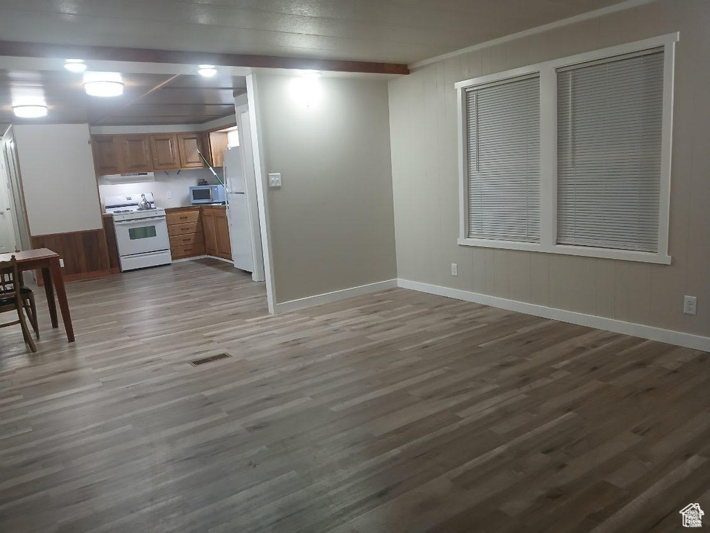 Kitchen with white appliances, wood finished floors, baseboards, and light countertops