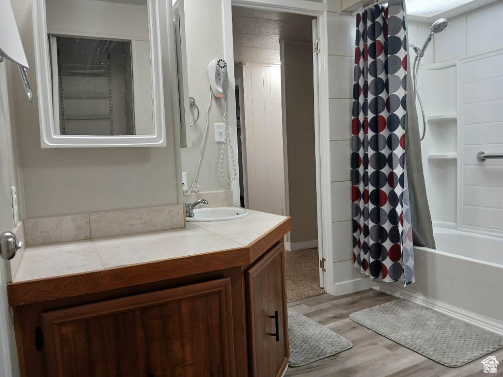 Bathroom featuring vanity, wood finished floors, and shower / bath combo with shower curtain