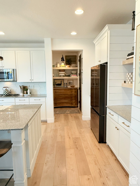 Kitchen featuring appliances with stainless steel finishes, white cabinetry, recessed lighting, open shelves, and tasteful backsplash