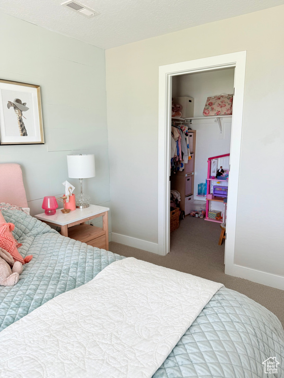 Bedroom with a spacious closet, carpet flooring, and a closet