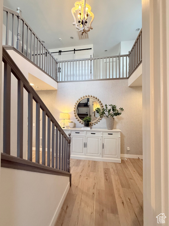 Stairs with a chandelier, hardwood / wood-style floors, baseboards, and a high ceiling
