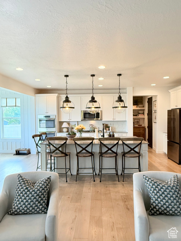Living area featuring light wood-style flooring, a textured ceiling, and recessed lighting